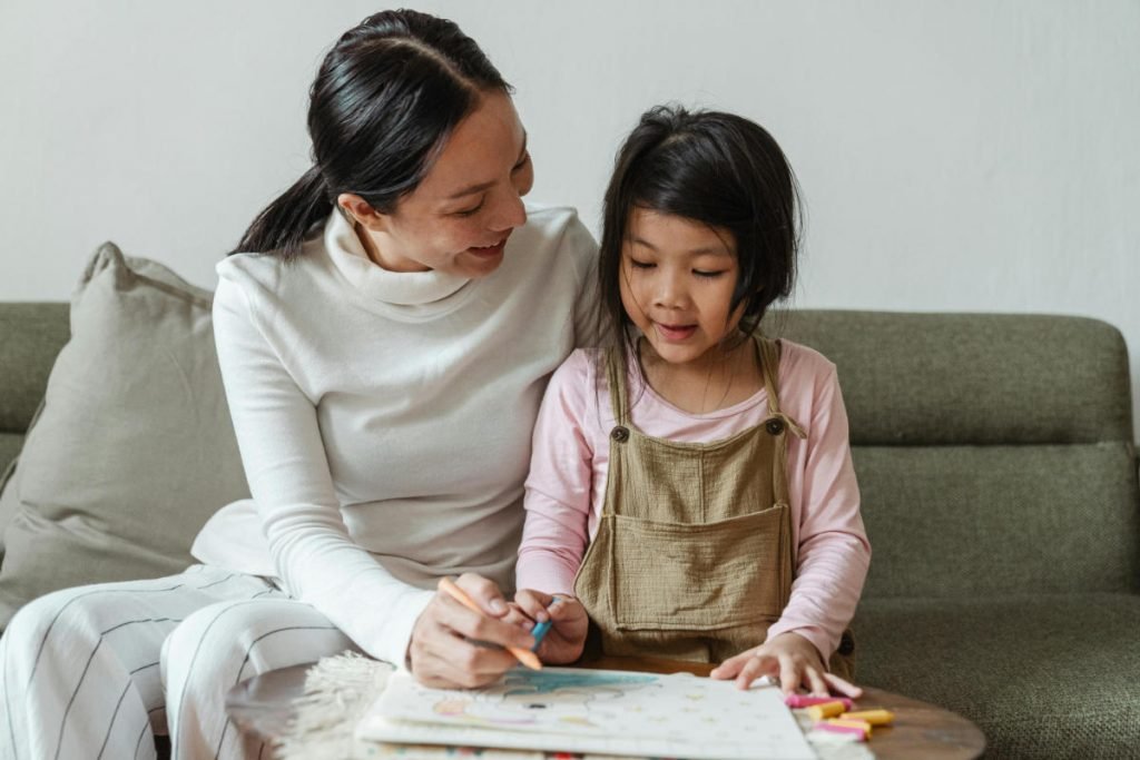 Smiling woman tutoring ethnic girl at home